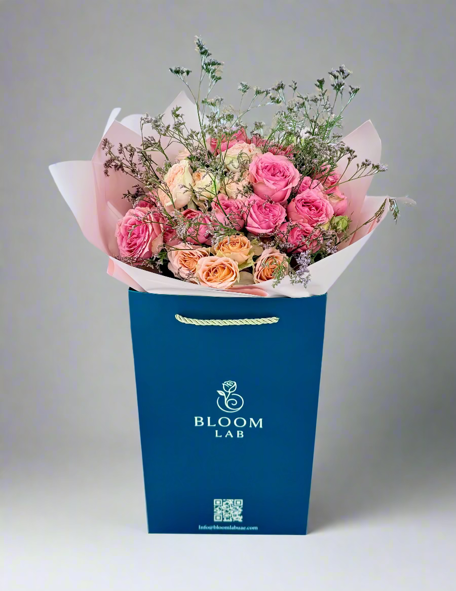 Mixed pink and peach roses bouquet with greenery, wrapped in blush pink paper – available for same-day flower delivery in Dubai.
