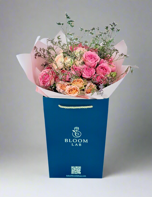 Mixed pink and peach roses bouquet with greenery, wrapped in blush pink paper – available for same-day flower delivery in Dubai.