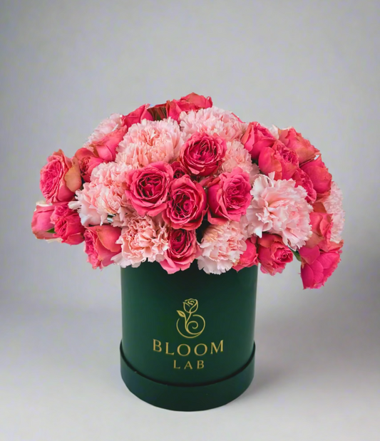 Elegant mix of pink roses and carnations arranged in a dark green Bloom Lab box – available for same-day flower delivery in Dubai.